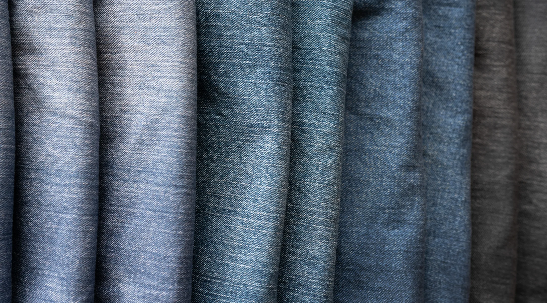 Folded WTRLSS denim across the wash range — light wash at left fading through to charcoal