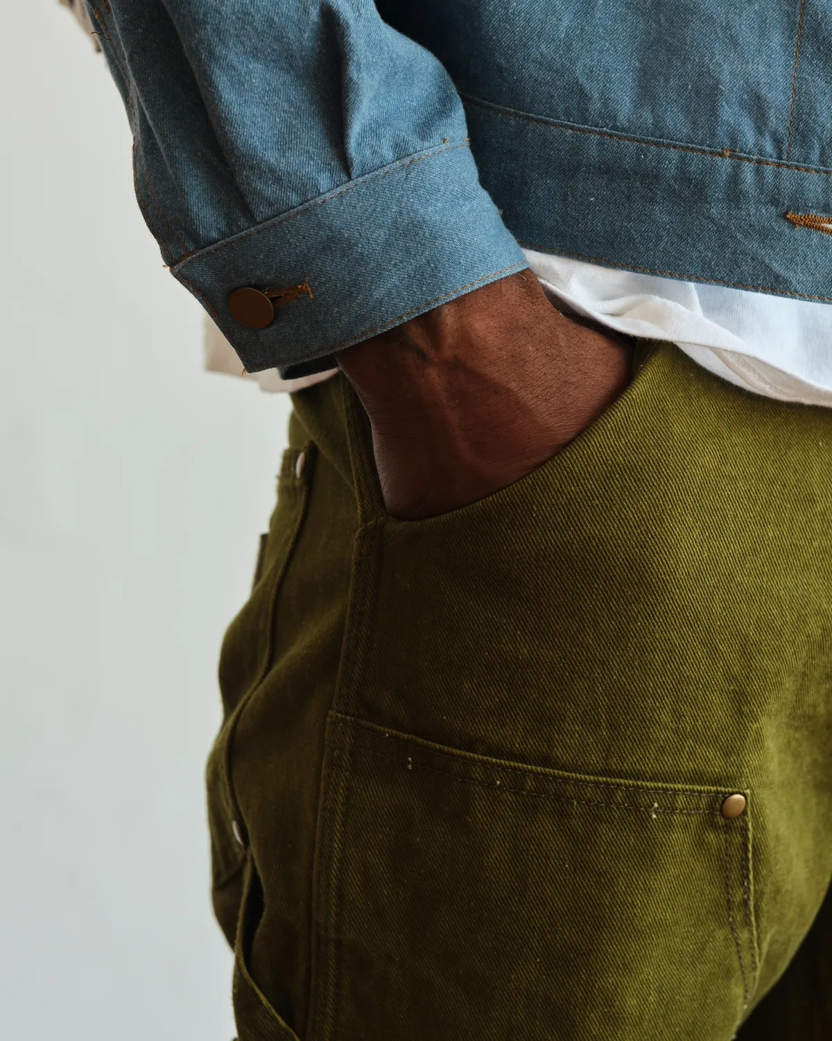 A hand in the pocket of WTRLSS olive carpenter pants — feeling the dry-dyed fabric